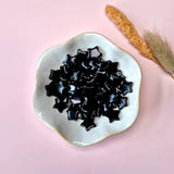 Edelsteen Zwarte Obsidiaan Mini Ster (1.5 cm), stervormige edelsteen kralen op een witte schaal