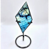 Labradorite gemstone with iridescent blue-green sheen mounted on a metal display stand