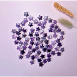 Edelsteen Amethist Mini Ster, Moonlight Gemstones: star-shaped amethyst chips scattered on pink background