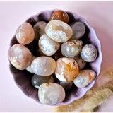 Edelsteen Cherry Blossom Agate palm stones, 3–6 cm, peach and white patterns in a purple bowl
