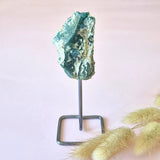 Ruwe edelsteen op standaard, ca. 12 cm, turquoise en groen tinten op metalen sokkel