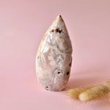 Druzy rose amethyst freeform stone with pale pink hues and white marbling on a pink background
