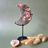 Rode druzy mosagaat maan op standaard, 10–12 cm, met roze-rode patronen en kristallen.
