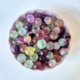 Edelsteen mini Regenboog Fluoriet bollen (1–2 cm) in een roze schaal, kleurrijk en glanzend.