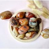 Moonlight Gemstones Sardonyx handstones, polished palm stones (4–7 cm), set of 12 with orange-tan banding in a wooden bowl