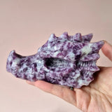 Paarse mica drakenschedel edelsteen sculptuur met witte vlekken, in hand gehouden