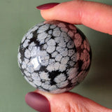 Snowflake Obsidiaan Bol 4–5 cm, zwart met witte sneeuwvlokken, in de hand gehouden