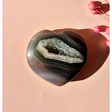 Grijze druzy agaat hartvorm met open geode in midden en banding rondom