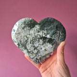 XL edelsteen druzy mosagaat hart met groen-grijs patroon, in hand gehouden