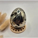 Edelsteen Pyriet bol (40–50 mm) met druzy kristallen; gepolijst zilvergrijs, op houten standaard.