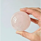 Rose quartz crystal sphere, 63mm diameter, 350g, held in hand