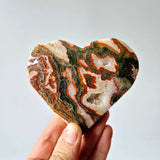 Rode druzy mosagaat hart steen held in hand, multicolor banded pattern