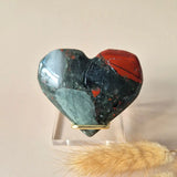 Heart-shaped African bloodstone palmstone with red and green color bands, mounted in a gold-tone ring.