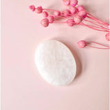 Bergkristal Worry Stone by Moonlight Gemstones, white quartz oval on pink background.