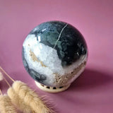 Moss agate druzy geode sphere, 90mm, 1028g, dark green/black exterior with white crystal interior on a display stand