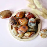 Moonlight Gemstones Sardonyx palm stones set; polished, banded orange and cream hues in a wooden bowl