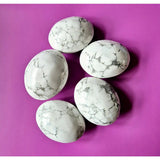 Kristal Howliet palmstones by Moonlight Gemstones - six white howlite stones with gray veining on purple background