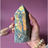 XL Labradorite tower with rainbow flash in purple and orange, held in hand