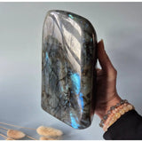 Moonlight Gemstones labradorite freeform crystal with intense blue iridescent flashes, held in hand