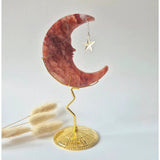 Fire quartz crescent moon on a gold-toned stand with hanging star charm, 10 cm