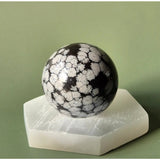 Snowflake Obsidian sphere, black with white snowflake veining, 4–5 cm, on a white display stand