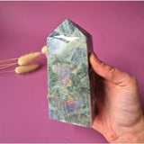 XL labradorite gemstone tower in purple and orange with rainbow flash, held in hand