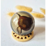 Moonlight Gemstones Ocean Jasper 50mm ball in red-orange with a unique pattern on a wooden stand