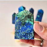 Azurite gemstone towers set (4 pieces) in blue-green hues with black matrix, held in hand