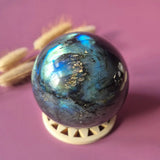Labradoriet bol van Moonlight Gemstones; edelsteen sphere met flash, 50–85 mm, iriserend blauw-groen.