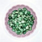 Kristalgroene aventurijn stenen, getrommeld 0,5–2 cm, in roze schaal.