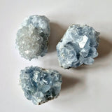 Celestite crystal clusters from Moonlight Gemstones; three rough blue-gray specimens.