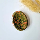 Unakiet worry stone, oval polished gemstone in green with pink coral mottling.