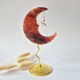 Fire Quartz crescent moon sculpture by Moonlight Gemstones on a gold-tone stand with a hanging star