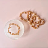 Sunstone edelsteen chips armbanden; peachkleurige kralen, set van twee op roze achtergrond