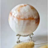 Moonlight Gemstones XL Fire Quartz crystal ball, 88 mm, cream-white with orange veins on ornate metal stand