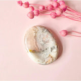 Crazy Agate Worry Stone, oval banded agate in pale peach and gray on pink background.