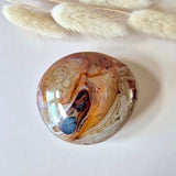 Polished sardonyx palmstone sphere with red, orange and cream banding, 5–10 cm