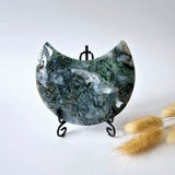 Moonlight Gemstones moss agate crescent moon on a stand with green-blue druzy patterns.
