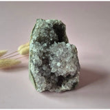 Amethist geode met calciet; kristalcluster in open holte tegen roze achtergrond