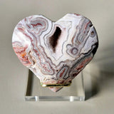 Mexican Crazy Lace Agate heart with stand, pink, white and gray banded stone with crystal-filled center on a clear stand
