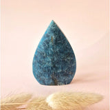 Blue apatite teardrop gemstone standing upright, deep blue marbling visible.