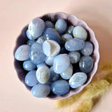 Moonlight Gemstones blue lace agate palm stones, polished blue tumble stones in a pink dish.