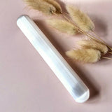 Seleniet massagestick, 15 cm, white translucent crystal with beige dried grasses on pink background