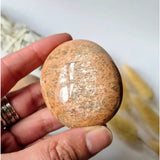 Peach moonstone palmstone held in hand, polished worry stone for calm and balance