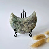Edelsteen Mosagaat Maan op Standaard met druzy patroon in groene tinten, op zwart metalen standaard.
